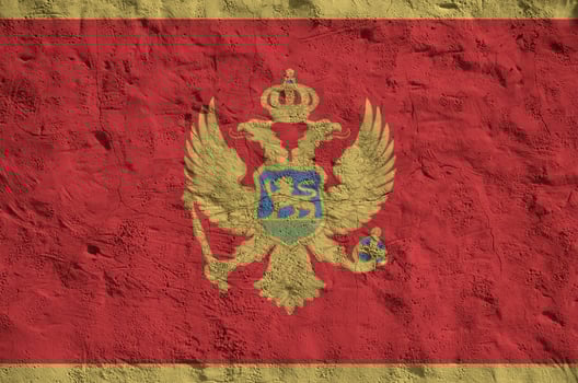 Montenegro flag depicted in bright paint colors on old relief plastering wall. Textured banner on rough background photo