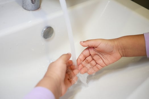 child making a cleansing gesture with soap and water on hands photo