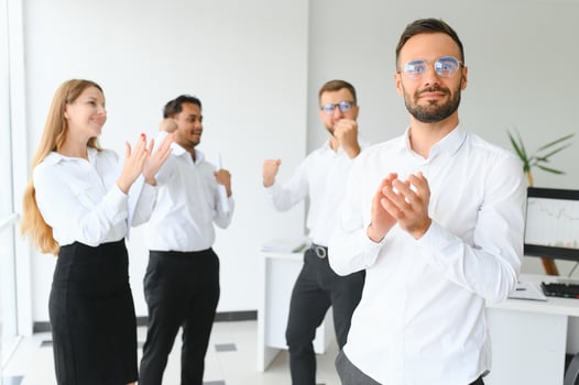 Team leader stands with coworkers in background photo