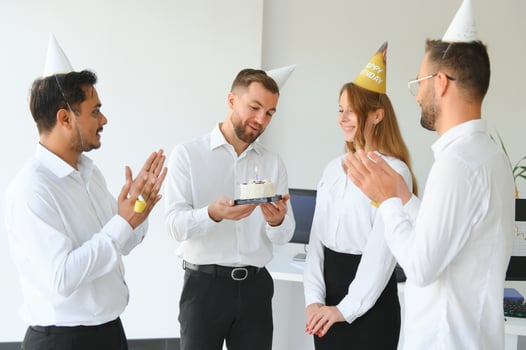 Happy businesswoman holding Birthday cake while making surprise party with her colleagues in the office. photo