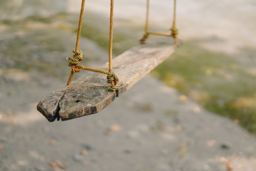 A swing made from wood hanging on a tree in the park, natural background. Outdoor and relaxation concept. photo