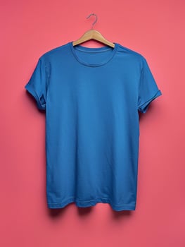 Blue T-Shirt Hanging on Wooden Hanger Against Pink Background photo