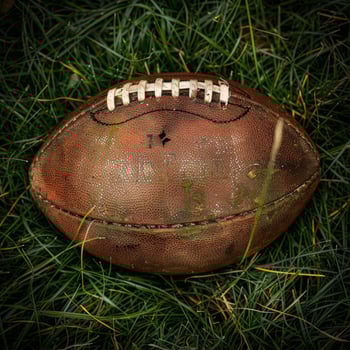 Worn Leather American Football Resting on Green Grass photo