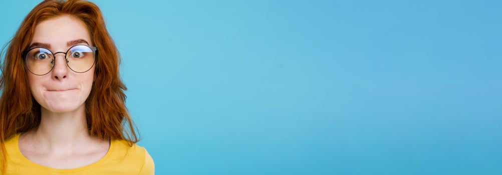 Headshot Portrait of happy ginger red hair girl with funny face looking at camera. Pastel blue background. Copy Space photo