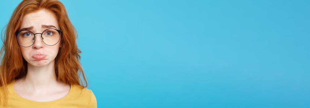 Headshot Portrait of happy ginger red hair girl with freckles smiling looking at camera. Pastel blue background. Copy Space. photo