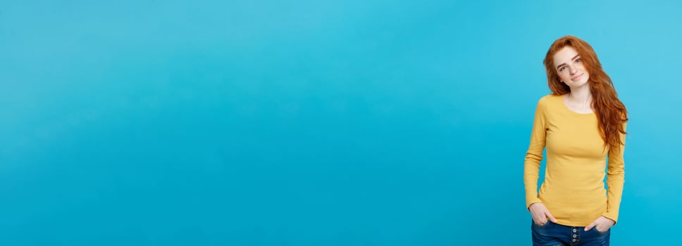 Portrait of young beautiful ginger woman with freckles cheerfuly smiling looking at camera. Isolated on pastel blue background. Copy space. photo