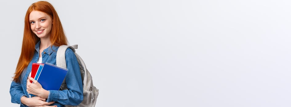 Time to school. Lovely cheerful modern redhead female with backpack holding notebooks heading college, smiling amused, heading back to class after break, standing white background photo