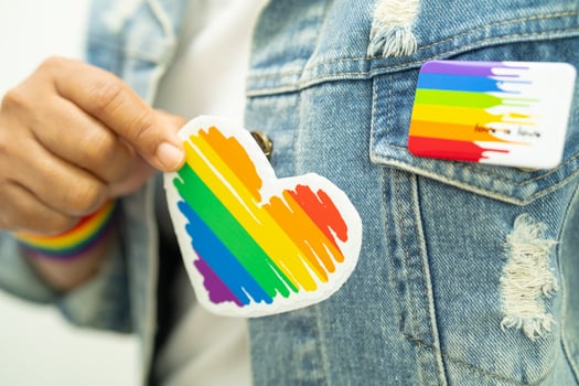 Asian lady wearing rainbow flag wristbands and hold red heart, symbol of LGBT pride month celebrate annual in June social of gay, lesbian, bisexual, transgender, human rights. photo