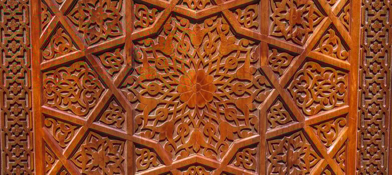 Arabic Uzbek Islamic patterns arabesque ornament on brown wooden carved door in Uzbekistan close up photo