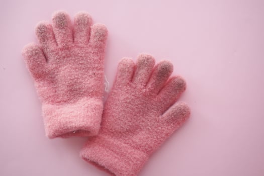 Soft Pink Winter Gloves on Pastel Pink Background. Cozy fashion accessory for women in cold weather photo