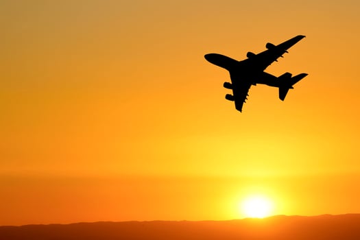 Airplane Silhouette Against Vibrant Orange Sunset Sky, Capturing the Essence of Travel and Adventure in a Stunning Aerial Scene photo