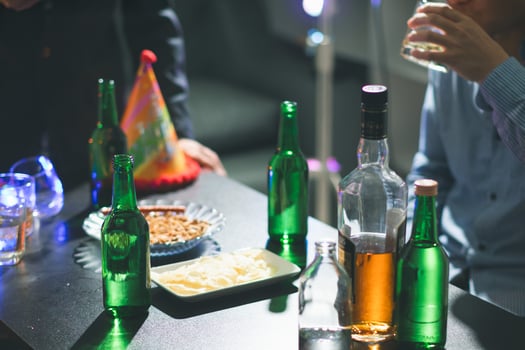 In the background, many bottles of alcohol were placed on the table at the party. Bottles of alcohol were given out to friends and group members to drink together in celebration of business success. photo