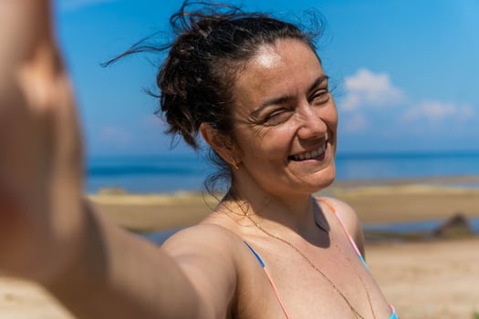 A woman in a swimsuit takes a selfie on the beach photo