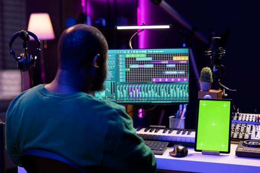 Songwriter composer mixing and mastering tracks next to greenscreen, operating on digital audio pc interface to add sound effects on new recordings. Technician in home studio. photo