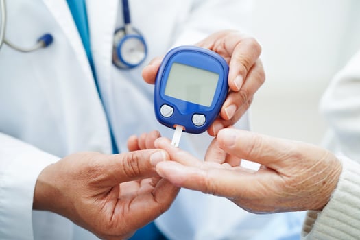 Asian doctor using digital glucose meter for check sample blood sugar level to treatment diabetes. photo