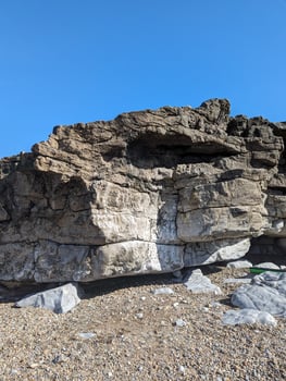 Rock Formation at a Pebble Beach Under Clear Blue Sky photo
