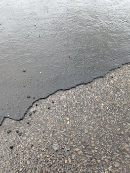 Access road with deteriorating asphalt, gravel, and rainwater accumulation in Wales. photo