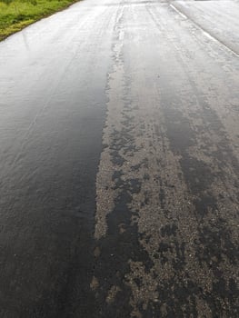 Failing road surface in Wales, showing deterioration, construction site, rain-wetted tarmac. photo
