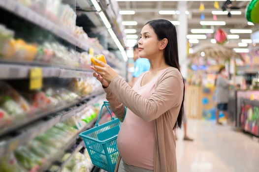 Beautiful pregnant woman shopping healthy food at grocery shop photo