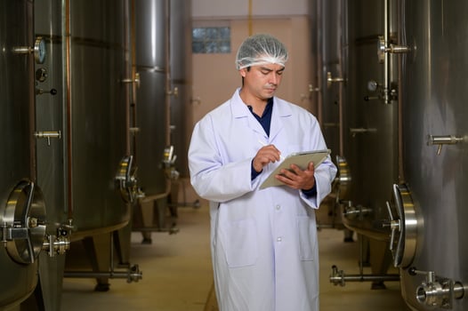 Professional winemaker controlling wine making process and quality at winery factory photo