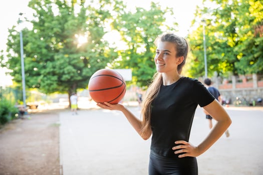 A woman is holding a basketball in a park ready to play a game photo