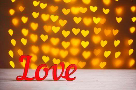 the inscription Love on a wooden background with beautiful hearts made of lights on a blurred background photo