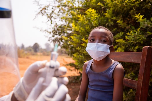 A doctor is about to vaccinate a child, close up on the child wearing a surgical mask photo
