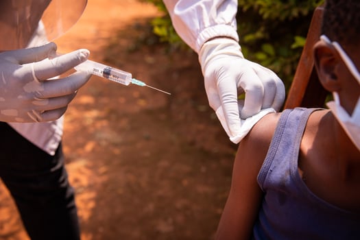 Close-up of a doctor's hand with a syringe about to inject the vaccine to a child in africa. Vaccination concept photo