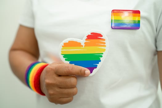 Asian lady wearing rainbow flag wristbands and hold heart, symbol of LGBT pride month celebrate annual in June social of gay, lesbian, bisexual, transgender, human rights. photo