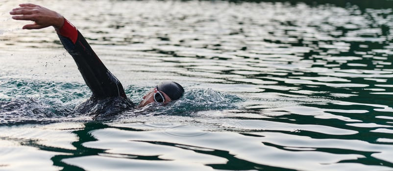 A professional triathlete trains with unwavering dedication for an upcoming competition at a lake, emanating a sense of athleticism and profound commitment to excellence. photo