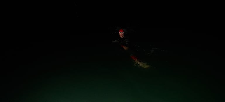 Authentic triathlete swimmer having a break during hard training on night photo