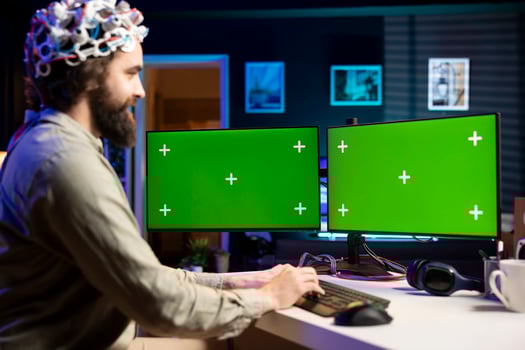 Happy developer using EEG headset device translating thoughts into isolated screen desktop PC commands. Smiling IT specialist controlling mockup multi monitor computer functions using mind photo