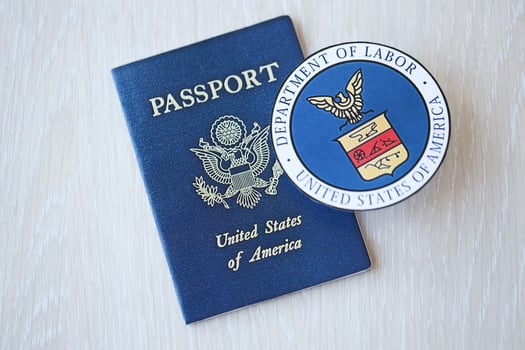 KYIV, UKRAINE - MARCH 9, 2024 US Department of Labor seal and United States passport on wooden table photo
