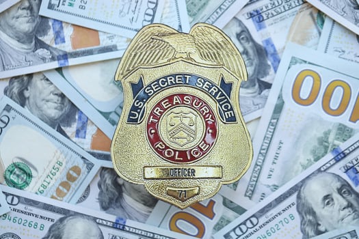 KYIV, UKRAINE - MARCH 9, 2024 US Treasury Police Secret Service Officer badge on many US hundred dollar bills photo