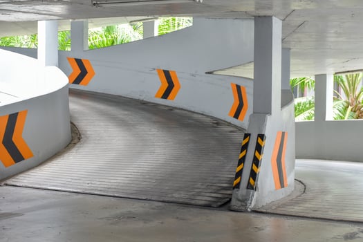 Entrance to the circular parking building go down and yellow warning symbol in natural and sunlight background at public parking. photo