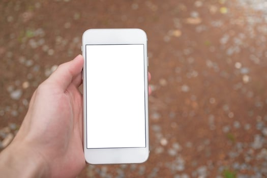 Man hand holding modern smartphone mockup with blank white screen in blurred background for concept of social media and marketing. photo