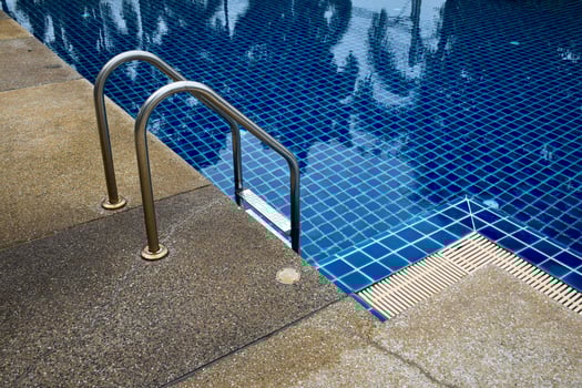 View of the swimming pool and swimming pool ladder decorated with gravel walkways in vintage tones. photo
