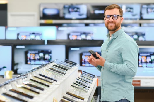 guy in an electronics store chooses a cell phone to buy photo