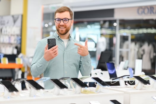 happy young man choosing a new mobile in a tech store photo