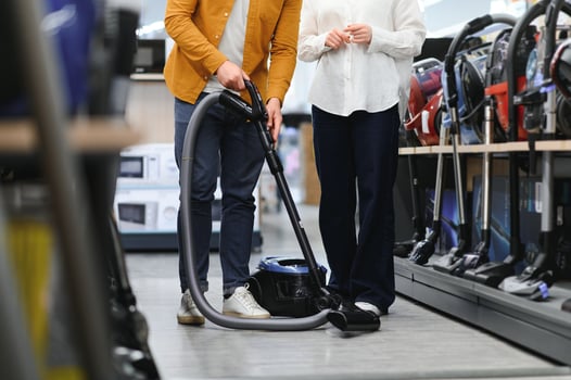 Young beautiful couple buying new vacuum cleaner at tech store. Having fun shopping time photo