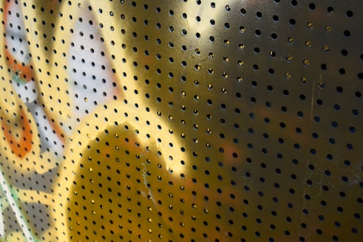 Close-up a metal surface with many holes between it and different colors smeared on the surface creates a beautiful pattern in a vintage tone background. photo
