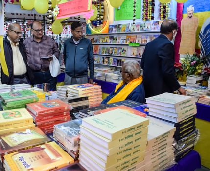 Delhi, India, May 17 2024 - Various age group people reading variety of Books on shelf inside a book-stall at Delhi International Book Fair, Books in Annual Book Fair at Bharat Mandapam complex photo