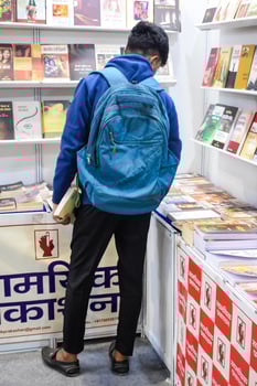 Delhi, India, May 17 2024 - Various age group people reading variety of Books on shelf inside a book-stall at Delhi International Book Fair, Books in Annual Book Fair at Bharat Mandapam complex photo
