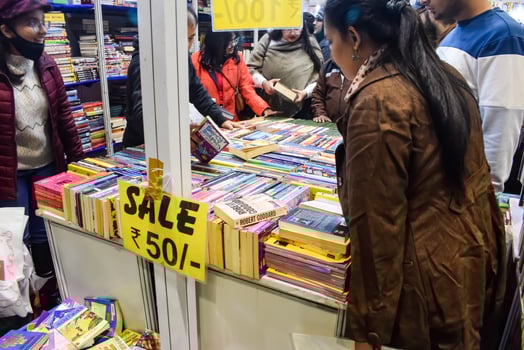 Delhi, India, May 17 2024 - Various age group people reading variety of Books on shelf inside a book-stall at Delhi International Book Fair, Books in Annual Book Fair at Bharat Mandapam complex photo