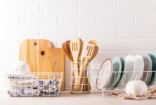 A set of ceramic plates in the dryer, wooden cooking tools, cutting boards, many different towels in the storage area. Trendy eco style in kitchen photo