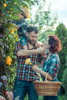 Happy parents with their little son kissing in nature in flowers photo