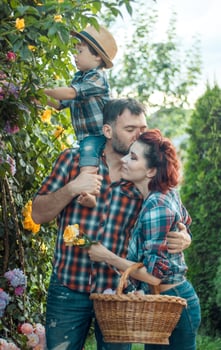 Happy parents with their little son kissing in nature in flowers photo
