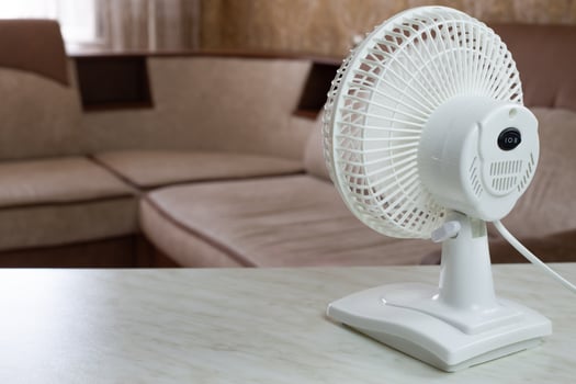 White fan on the table is turned on to cool the air in room rear view photo