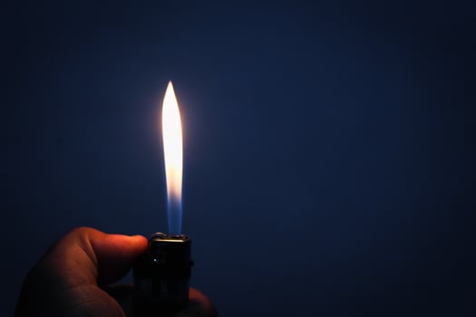 Gas lighter burns in the dark photo