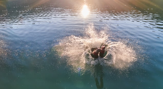 Triathlon athlete swimming on lake in sunrise wearing wetsuit photo